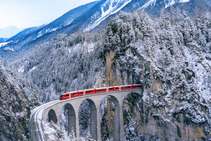 Aerial view of Train passing through famous mountain in Filisur, Switzerland. Landwasser Viaduct world heritage with train express in Swiss Alps snow winter scenery.