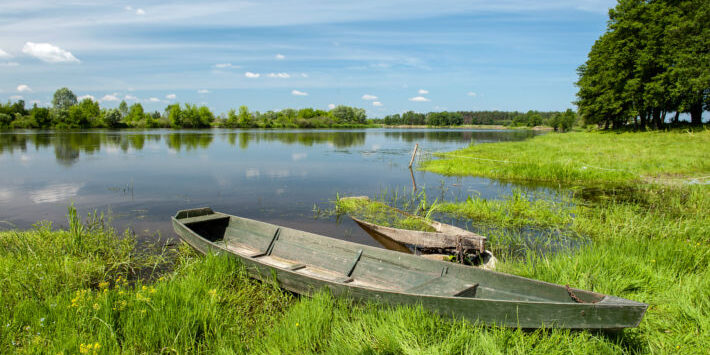 Kleines Holzboot an einem Seeufer in der Masurischen Seenplatte in Polen.