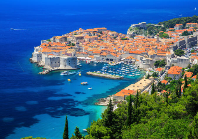 Blick auf die historische Altstadt von Dubrovnik während einer Busreise, mit den beeindruckenden Stadtmauern und dem azurblauen Adriatischen Meer im Hintergrund.