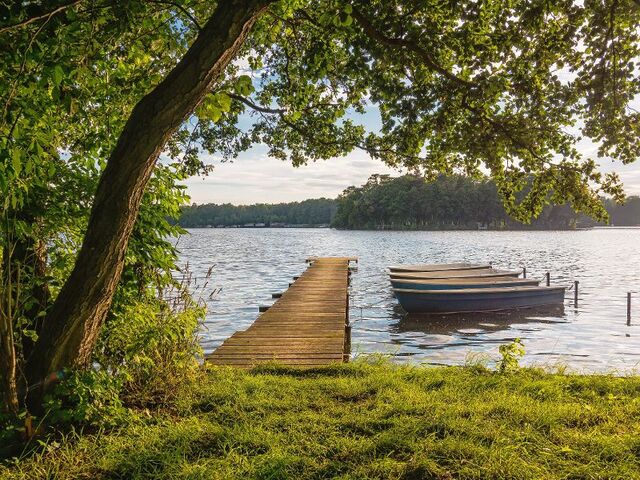 Ein Steg und Boote am See.