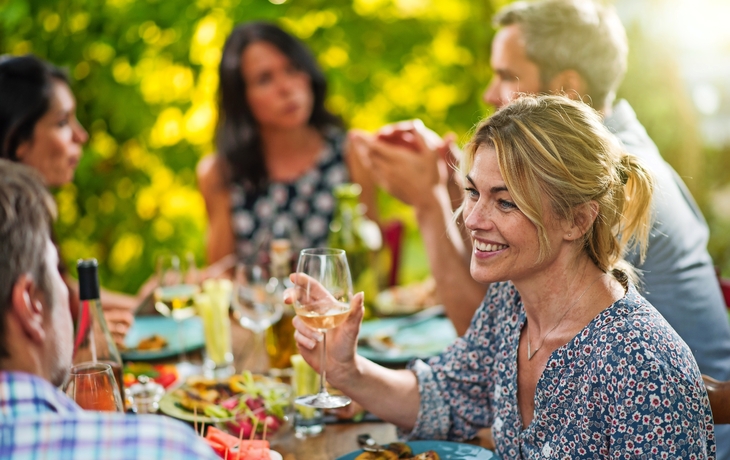 Gruppe Freunde, die um einen Tisch auf einer Terrasse zu Mittag essen
