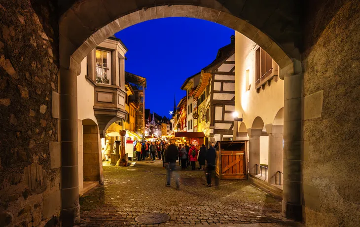 Atmospheric View Through the City Gate of Stein am Rhein onto the Festively Lit Christmas Market at Dusk